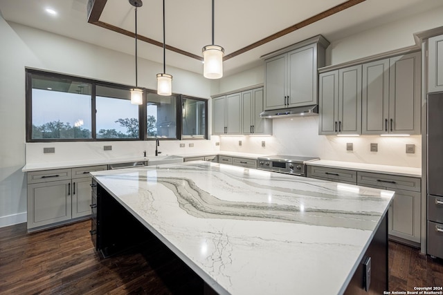 kitchen featuring light stone countertops, dark hardwood / wood-style flooring, a kitchen island, and hanging light fixtures