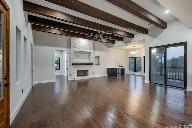 unfurnished living room with a stone fireplace, beamed ceiling, dark hardwood / wood-style floors, and ceiling fan with notable chandelier