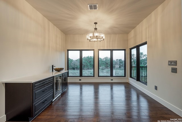 unfurnished dining area featuring dark hardwood / wood-style floors and an inviting chandelier