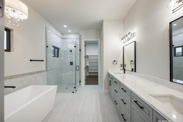 bathroom with separate shower and tub, vanity, and a notable chandelier