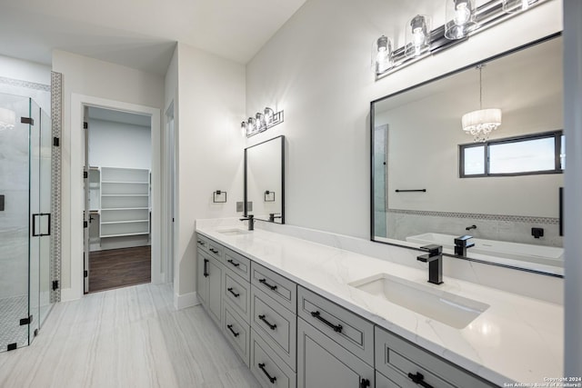 bathroom featuring separate shower and tub, vanity, and an inviting chandelier