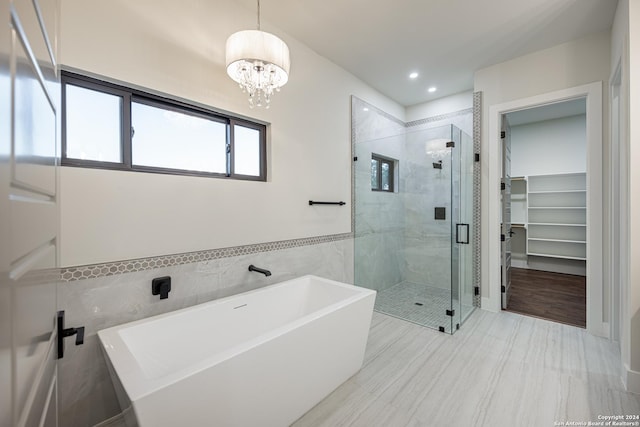 bathroom with shower with separate bathtub, tile walls, and a notable chandelier