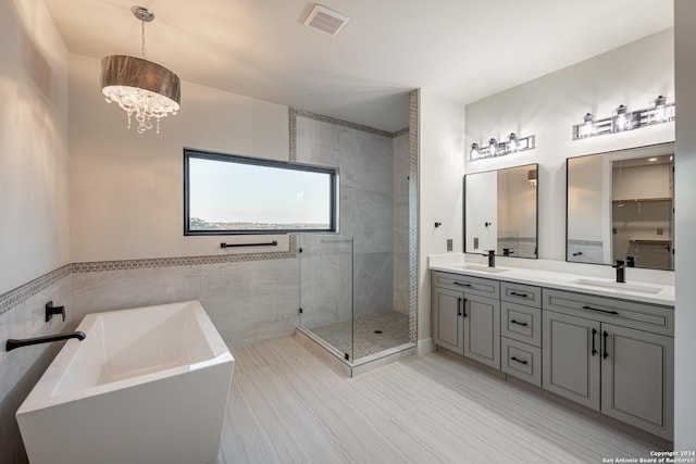 bathroom featuring vanity, separate shower and tub, tile walls, and a chandelier