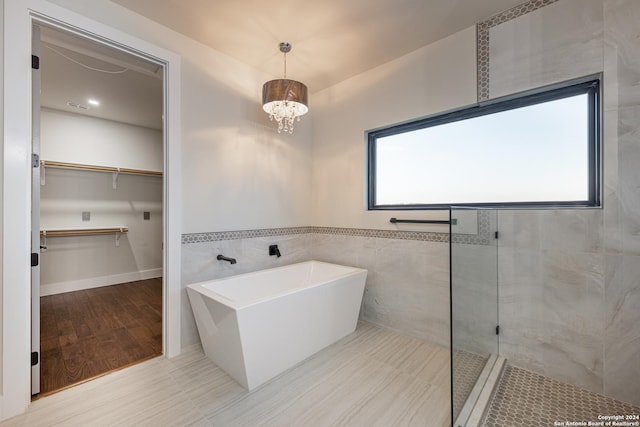 bathroom with tile patterned floors, tile walls, a wealth of natural light, and a chandelier