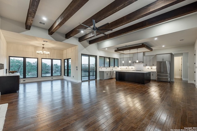 unfurnished living room with a towering ceiling, beamed ceiling, dark wood-type flooring, and ceiling fan with notable chandelier