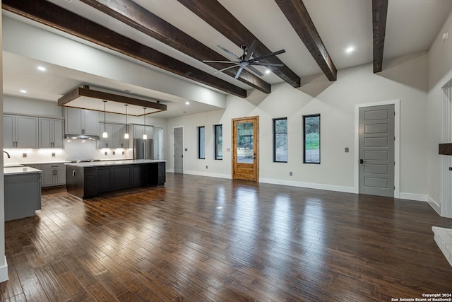 unfurnished living room with beamed ceiling, ceiling fan, and sink