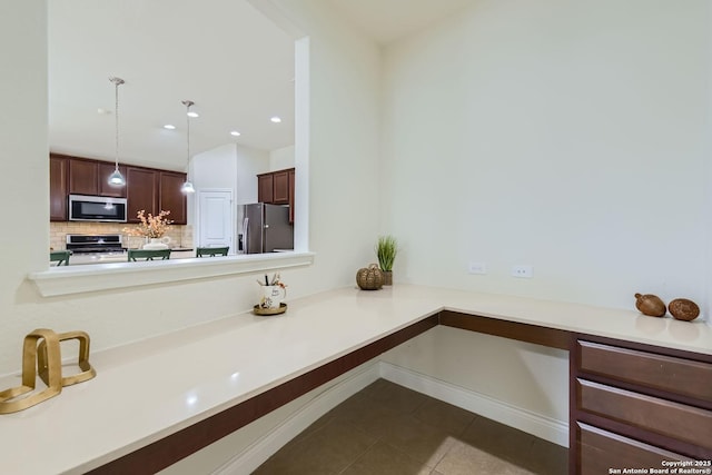 kitchen with decorative backsplash, kitchen peninsula, stainless steel appliances, dark tile patterned floors, and pendant lighting