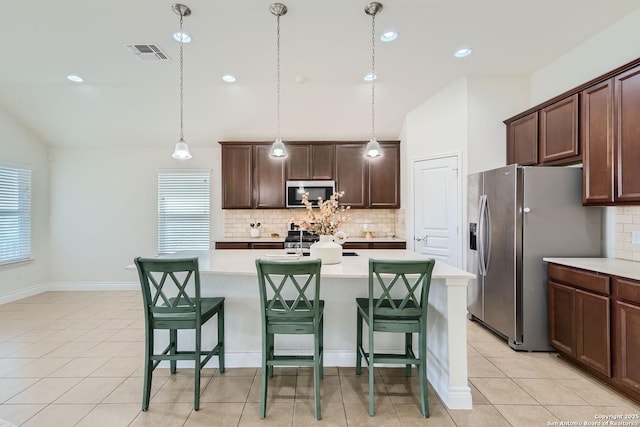 kitchen with a kitchen bar, dark brown cabinets, an island with sink, and stainless steel appliances