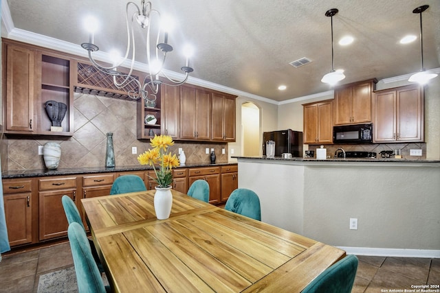 kitchen featuring dark stone counters, black appliances, crown molding, tasteful backsplash, and decorative light fixtures