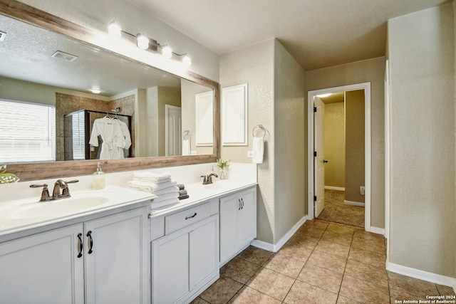 bathroom with a tile shower, tile patterned floors, vanity, and a textured ceiling