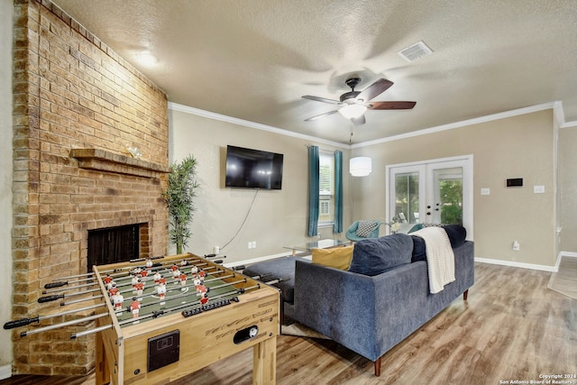 living room featuring ceiling fan, french doors, a textured ceiling, and ornamental molding