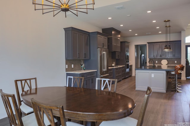 dining space with sink, dark hardwood / wood-style floors, and a notable chandelier