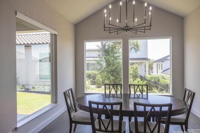 dining area featuring a wealth of natural light, hardwood / wood-style floors, vaulted ceiling, and an inviting chandelier