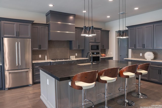 kitchen featuring pendant lighting, stainless steel appliances, and a kitchen island with sink