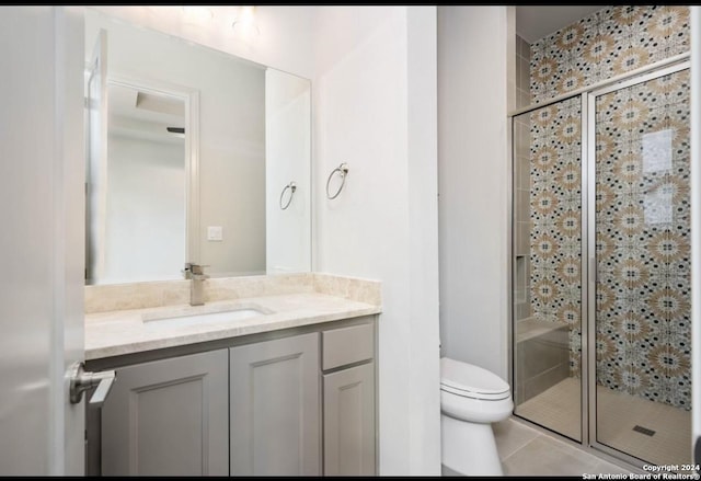 bathroom featuring tile patterned flooring, vanity, toilet, and a shower with door