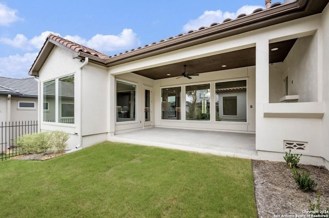 back of property featuring a lawn, a patio area, and ceiling fan