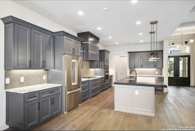 kitchen with tasteful backsplash, stainless steel appliances, sink, wood-type flooring, and hanging light fixtures