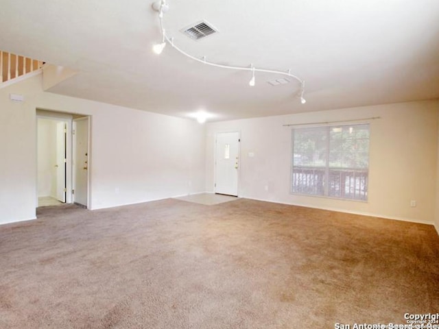 carpeted empty room with rail lighting