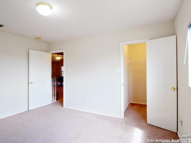 unfurnished bedroom with light colored carpet, a spacious closet, and a closet