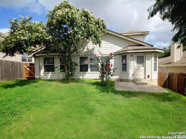 rear view of property featuring a lawn and a patio area