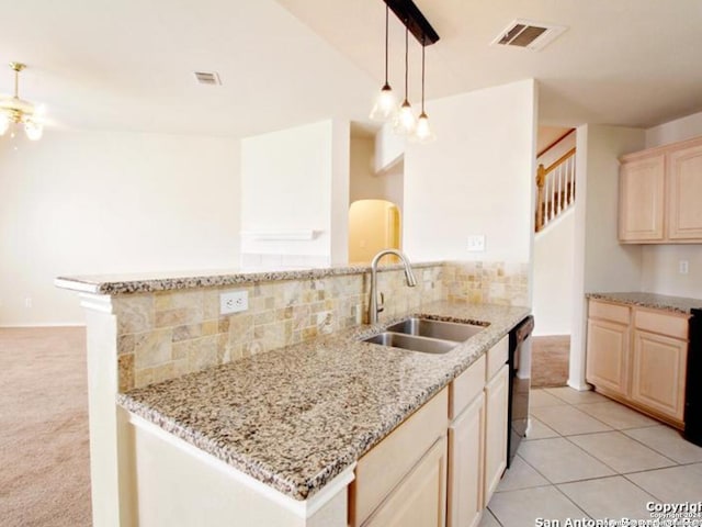 kitchen with kitchen peninsula, light stone countertops, sink, and hanging light fixtures