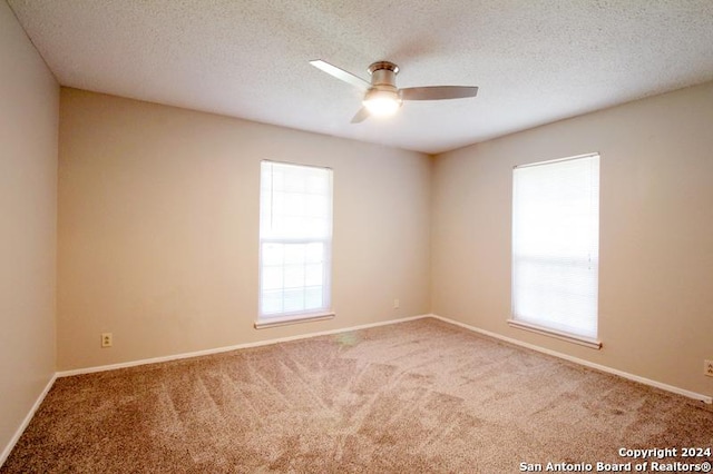 carpeted empty room with ceiling fan and a textured ceiling