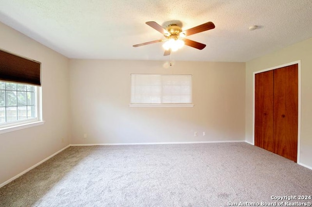 unfurnished bedroom featuring ceiling fan, a closet, carpet floors, and a textured ceiling