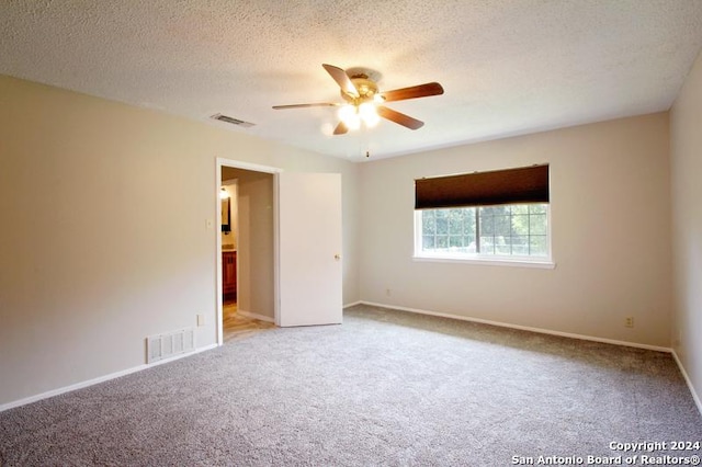 unfurnished room featuring ceiling fan, light colored carpet, and a textured ceiling