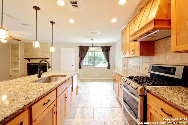 kitchen featuring custom exhaust hood, sink, hanging light fixtures, a brick fireplace, and gas stove