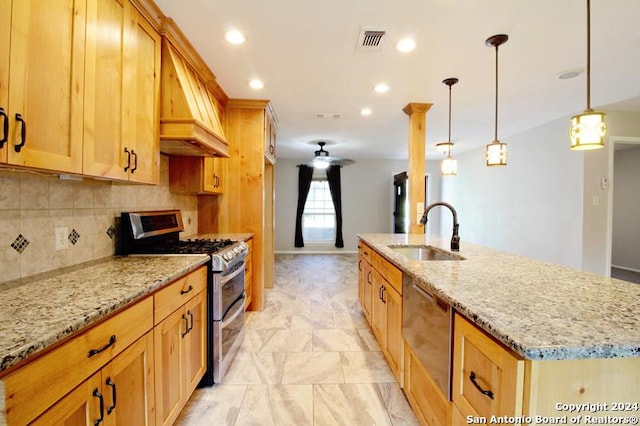 kitchen with sink, hanging light fixtures, light stone counters, a center island with sink, and appliances with stainless steel finishes