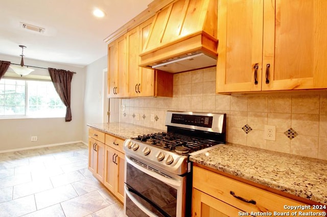 kitchen featuring gas range, tasteful backsplash, light stone counters, pendant lighting, and custom range hood