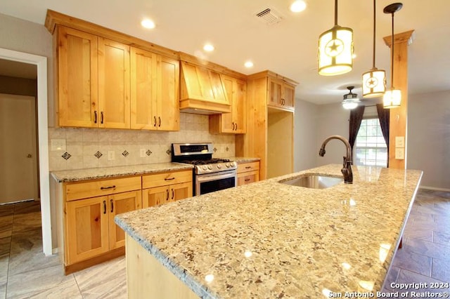 kitchen featuring pendant lighting, premium range hood, sink, stainless steel gas range, and light stone counters