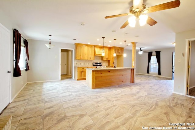 kitchen featuring ceiling fan, hanging light fixtures, stainless steel stove, and tasteful backsplash