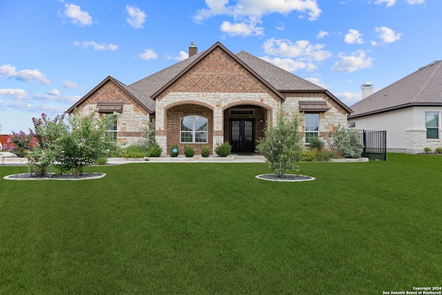 french country inspired facade featuring french doors and a front yard