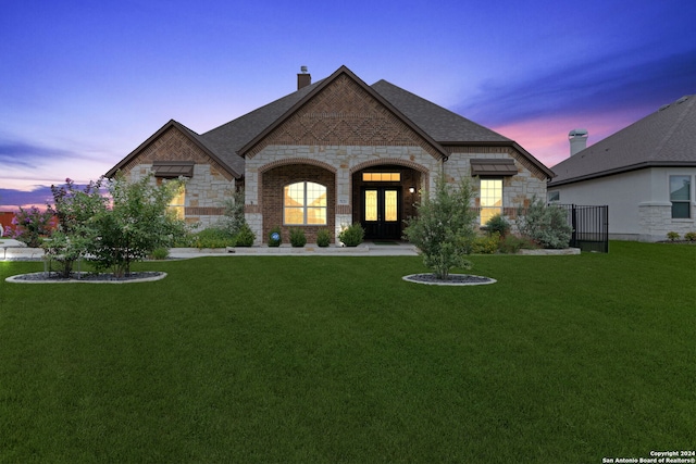 french country inspired facade featuring a lawn