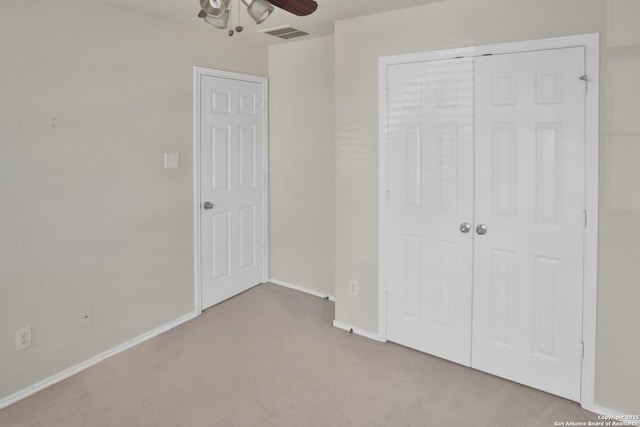 unfurnished bedroom with ceiling fan, light carpet, and a closet