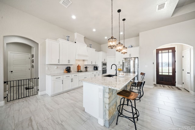 kitchen with white cabinetry, a kitchen island with sink, and sink