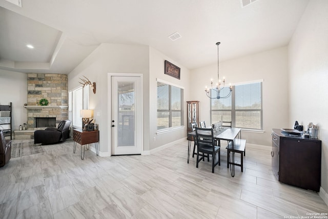 dining room featuring a stone fireplace and a chandelier