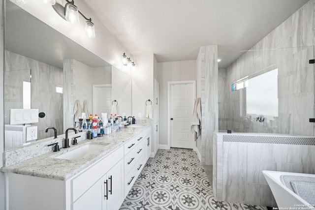 bathroom with tile patterned flooring, vanity, and tiled shower