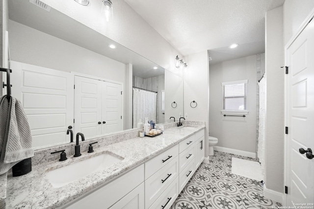 bathroom with tile patterned flooring, a textured ceiling, vanity, and toilet