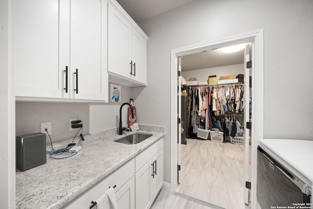 interior space featuring light stone counters, white cabinetry, and sink