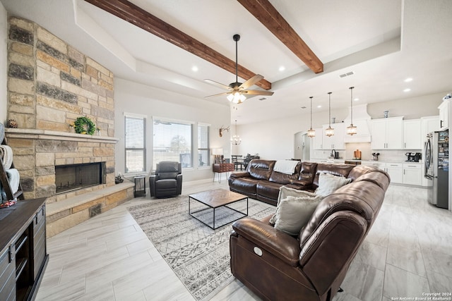 living room featuring ceiling fan, a fireplace, and beamed ceiling