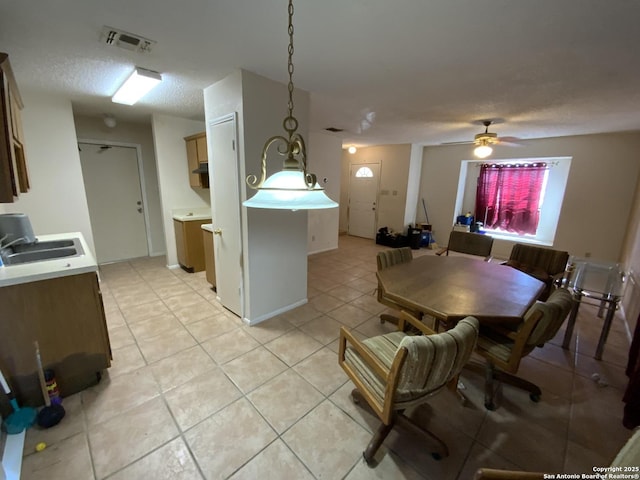 dining space featuring a textured ceiling, ceiling fan, light tile patterned floors, and sink