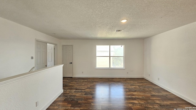 spare room featuring a textured ceiling and dark wood-type flooring