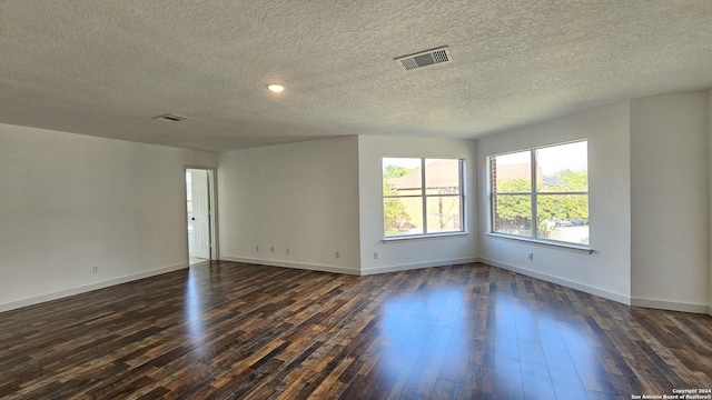 empty room with dark wood-type flooring and a textured ceiling