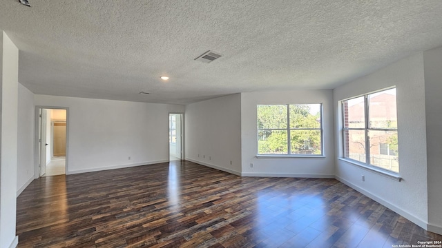 spare room featuring dark hardwood / wood-style floors and a textured ceiling