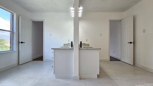 kitchen with white cabinetry, kitchen peninsula, and sink