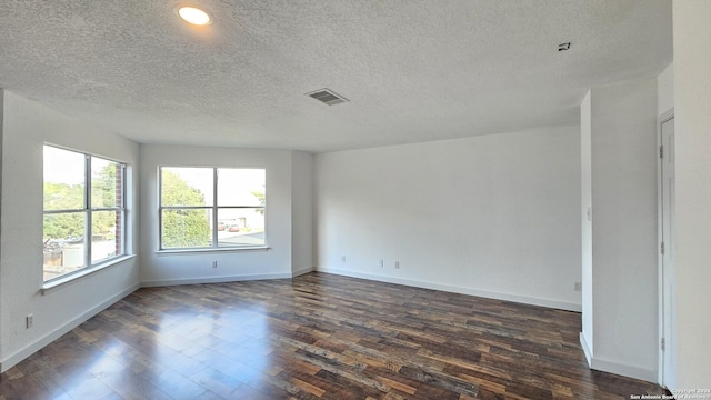 spare room with a textured ceiling and dark hardwood / wood-style floors