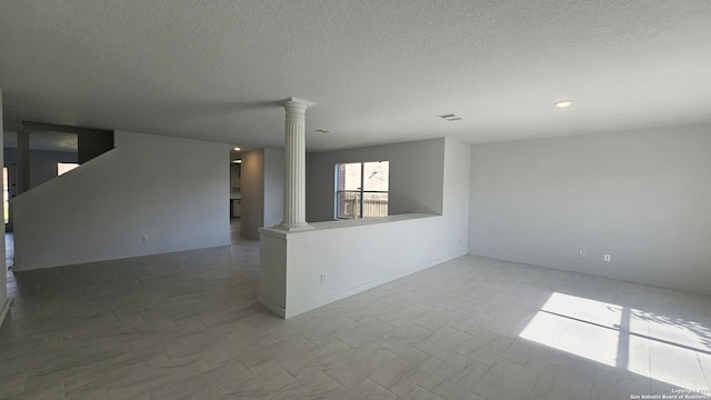 empty room featuring a textured ceiling and decorative columns