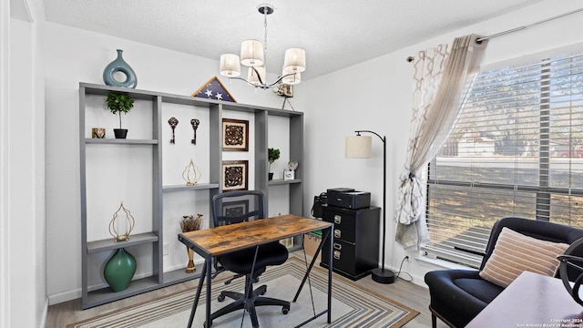 home office with light hardwood / wood-style floors, a textured ceiling, and an inviting chandelier